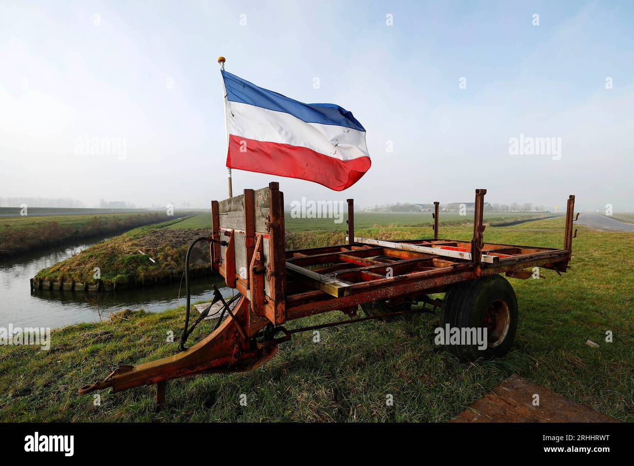 Der Bauernhof Landwinkel t `Zand in Den Bommel in den Niederlanden am 10.02.2023 Auf einem Traktoranhänger weht die auf den Kopf gestellte gestellte niederländische Flagge (normalerweise Rot,Weiss,Blau ) als ein Zeichen der Unterstützung für die Landwirte in den Niederlanden und des Protest und Widerstand gegen die verschieden Auflagen und Maßnahmen der holländischen Regierung. Foto: Norbert Schmidt, Duesseldorf Stock Photo